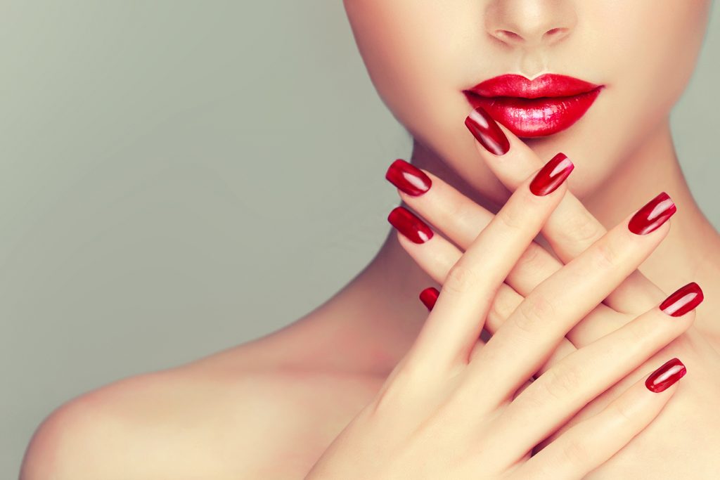 Beautiful girl showing red manicure nails
